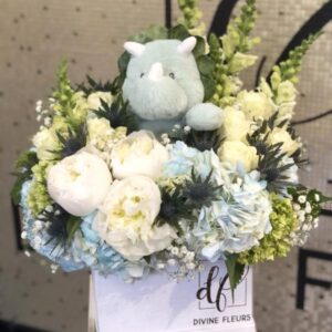 Welcome Baby arrangement, styled for a Boy or Girl. This adorable arrangement is made to order with highlights of blue or pink and a soft cute plush animal in the center.
