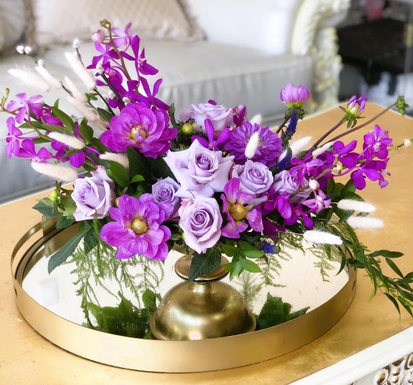 Purple Mokara orchids, purple Dahlias, lavender roses, and dark purple veronica, made in a beautiful golden tone pedestal vase.