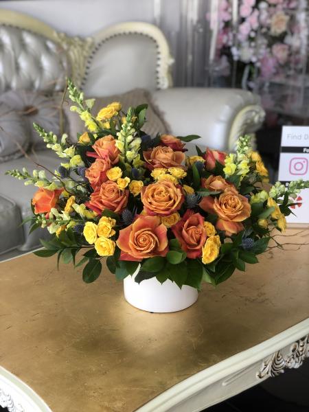 bicolor orange roses, yellow spray roses and accented with blue thistle and yellow snapdragons.